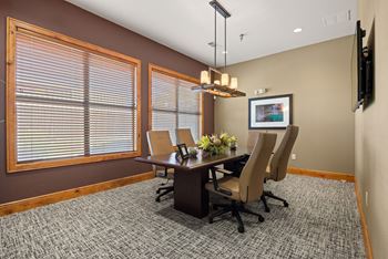 A conference room with a table, chairs, and a television on the wall.